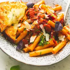 Pyszne maccheroni w sosie pomidorowym z kiełbaską, posypane parmezanem i podane z zapieczonym chlebem z serem.