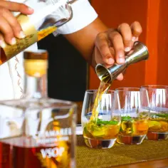 Barman nalewa rum Dictador do szklanek z lodem i miętą.