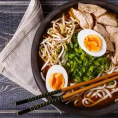 Pyszny ramen: makaron, kurczak, jajko na twardo, kiełki fasoli mung i szczypiorek w aromatycznym bulionie. Idealny posiłek, by dowiedzieć się, ramen co to jest.
