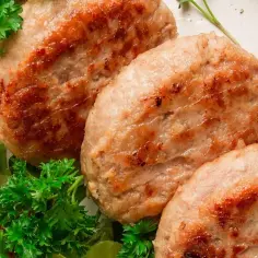 Apetyczne kotlety z indyka, rumiane i soczyste, podane z sałatką ze świeżych warzyw i natką pietruszki.