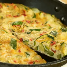 Pyszny omlet z cukinią i papryką, podany w żeliwnej patelni. Idealny na śniadanie lub lekki obiad.