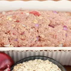 Masa na tradycyjny klops w naczyniu, obok cebula, płatki owsiane i jajka.
