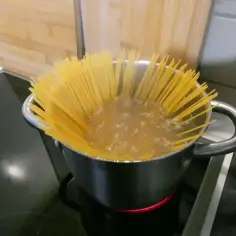 Długi makaron spaghetti gotuje się w garnku z wrzącą wodą na kuchence. Prosty sposób, jak ugotować makaron.