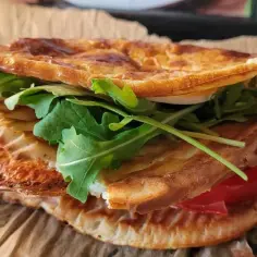 Pyszny wrap z serka wiejskiego, z rukolą i pomidorem, zapieczony na chrupko. Idealny na szybki posiłek.