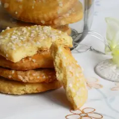 Stos ciasteczek kruchych babci, posypanych cukrem, w słoiku. Jeden kęs pokazuje ich kruchość.