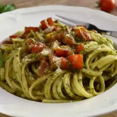 Pyszne pesto z makaronem, posypane parmezanem i kawałkami pomidorów. Idealne na szybki obiad.