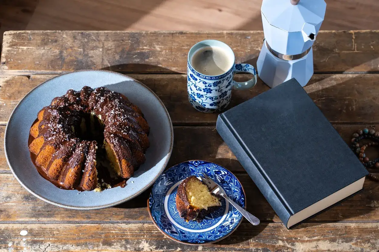 Pyszne ciasto brownie z płynną czekoladą, kawa i książka na drewnianym stole. Idealny zestaw na relaks.
