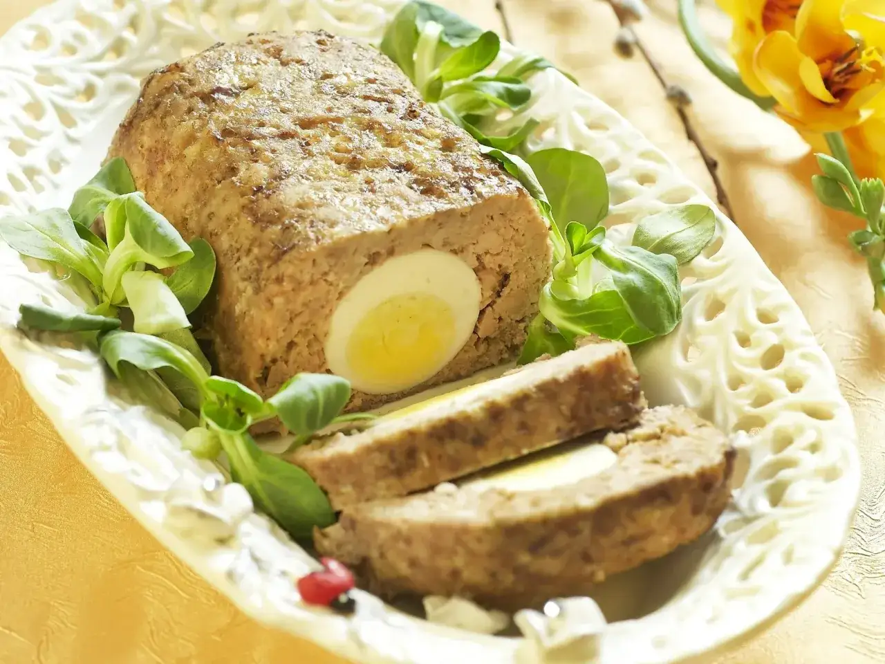 Tradycyjny klops z jajkiem w środku, udekorowany sałatką. Idealny przepis na wielkanocny stół.