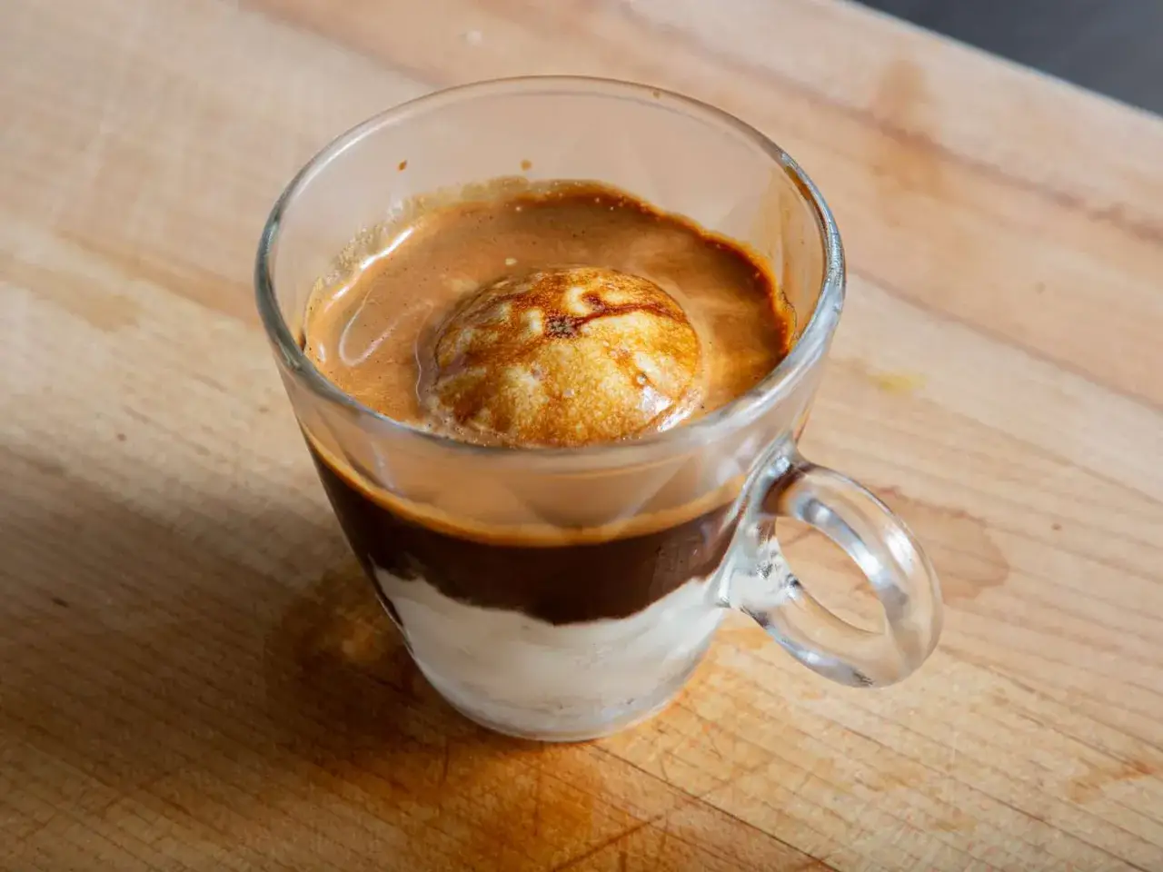 Pyszne affogato w szklance: gałka lodów waniliowych zalana gorącym espresso, tworząca kremową piankę.